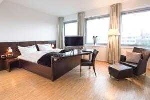 a hotel room with a bed, desk, chair and television at Altera Hotel in Oldenburg