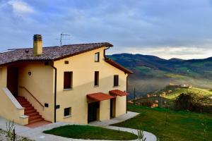 una casa blanca en una colina con montañas en el fondo en Agriturismo il Viandante, en Valfabbrica