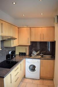 a kitchen with a washing machine and a sink at Kelpies Serviced Apartments MacGregor- 2 Bedrooms in Grangemouth