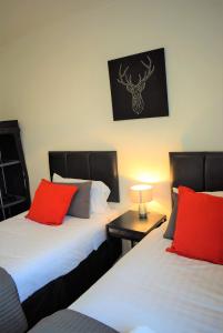 2 camas con almohadas rojas en una habitación en Kelpies Serviced Apartments MacGregor- 2 Bedrooms, en Grangemouth