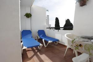 Un balcón con 2 sillas azules y una mesa. en BBQ apartamento Evita club, en Benalmádena