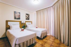 a hotel room with two beds and a window at Apartamentos Albatros Golf del Sur Tenerife in San Miguel de Abona +114 photos