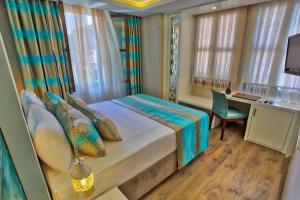 a bedroom with a bed and a desk and windows at Route Hotel Kaleici - Adult Only (12+) in Antalya