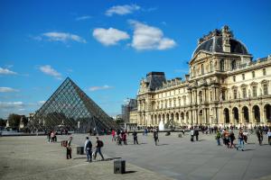 eine Gruppe von Menschen, die vor einem Gebäude spazieren in der Unterkunft Louvre Parisian ChicSuites in Paris