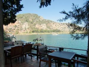 eine Terrasse mit Tischen und Stühlen neben einem Wasserkörper in der Unterkunft Hotel Happy Caretta in Dalyan