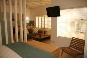 um quarto com uma cama, um sofá e uma televisão em Freshhh em Bloubergstrand