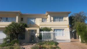 a large white house with a white fence at Freshhh in Bloubergstrand