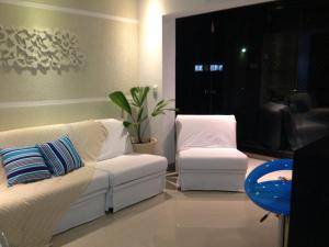 uma sala de estar com dois sofás brancos e uma planta em Flat Guaruja Diferenciado no Guarujá
