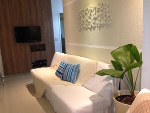 um sofá branco numa sala de estar com uma planta em Flat Guaruja Diferenciado no Guarujá