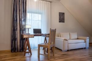 a living room with a desk with a laptop and a couch at Žvejų užeiga in Šiauliai