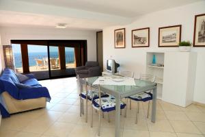 uma sala de estar com uma mesa de vidro e cadeiras em Terrazze Ponente e Levante - by Vacation Service em Cefalù