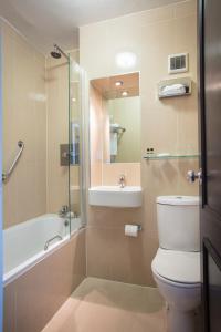 a bathroom with a toilet, sink, tub and shower at Thistle London Heathrow Terminal 5 in Hillingdon