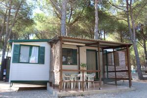 une petite maison avec deux chaises et une table dans l'établissement Villaggio Camping Lungomare, à Cropani