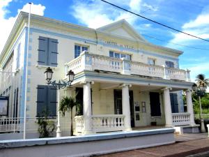 a white house with a balcony on a street at studio sympa in Port-Louis