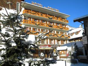 a hotel in the snow with a tree in front of it at Hôtel du Centre in Valloire