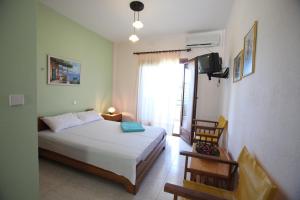 a bedroom with a bed and a tv and a window at Elena Apartments & Studios in Vourvourou