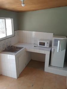 a small kitchen with a sink and a microwave at Pablo Guess House in Cap-Haïtien