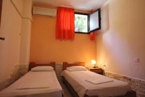 two beds in a room with a window at Elena Apartments & Studios in Vourvourou