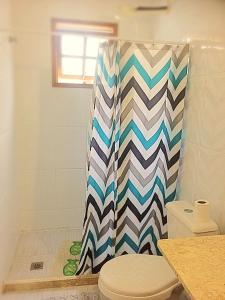 Un baño con inodoro y cortina de ducha. en Casa das Fragatas - Cama e Café, en Cabo Frío