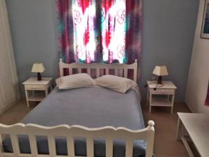 a bedroom with a bed and two tables with lamps at Papanikola House 2 in Astypalaia