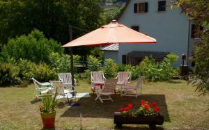 un grupo de sillas y un paraguas en un patio en Villa Du Sendenbach, en Muhlbach-sur-Munster