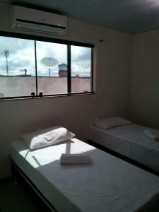 two beds in a room with a window at Hotel Reobot in Garanhuns