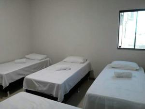 a room with three beds and a window at Hotel Reobot in Garanhuns