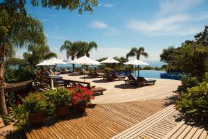 una terraza con sillas y sombrillas y una piscina en Resort Refúgio do Estaleiro en Porto Belo