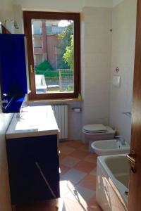a bathroom with a toilet and a sink and a window at Paola Apartments in SantʼAmbrogio di Valpolicella