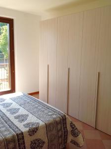 sypialnia z łóżkiem, białymi szafkami i oknem w obiekcie Paola Apartments w mieście SantʼAmbrogio di Valpolicella