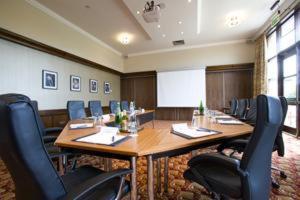 a conference room with a large wooden table and chairs at Buchan Braes Hotel in Peterhead