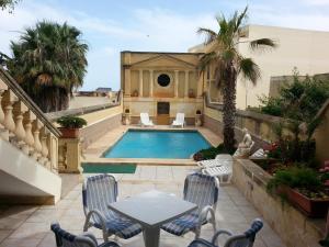a patio with a swimming pool with chairs and a table at Villa Palma in Sannat