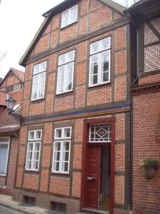 een bakstenen gebouw met een rode deur en witte ramen bij Lazy Elbfish in Lauenburg