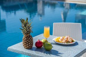 a pineapple and fruit on a table next to a pool at Alamis Hotel & Apartments in Tsilivi