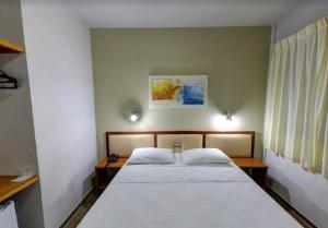 a bedroom with a large bed with white sheets at Ecos Hotel Tourist in Rolim de Moura