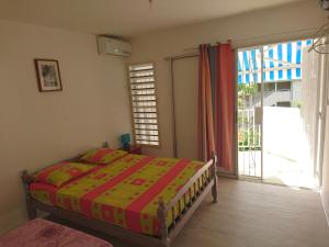 a bedroom with a bed and a large window at Location proche plage in Le Gosier