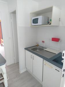 une petite cuisine avec un évier et un micro-ondes dans l'établissement Location proche plage, au Gosier