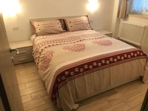 a bed in a small room with a bedspread and pillows at Genzianella Molveno-Andalo in Molveno