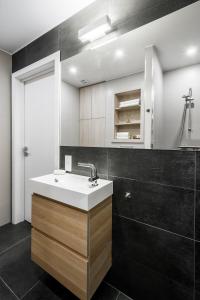 baño con lavabo blanco y azulejos negros en Uptown studio apartment en Vilna