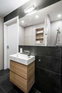 a bathroom with a white sink and black tiles at Uptown studio apartment in Vilnius
