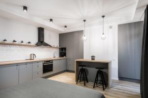 a kitchen with white cabinets and a counter with stools at Uptown studio apartment in Vilnius
