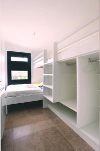 a white bedroom with a bed and a window at Le 27 in Malaucène