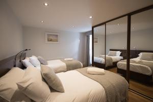 ポーツチュワートにあるOcean Breezeのベッド3台と鏡が備わるホテルルーム