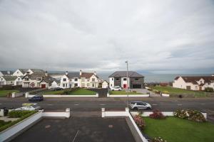 um parque de estacionamento com carros estacionados em frente a casas em Ocean Breeze em Portstewart