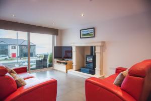 sala de estar con 2 sillas rojas y chimenea en Ocean Breeze, en Portstewart