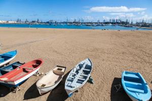 trois bateaux sur une plage avec un port en arrière-plan dans l'établissement Adorable urban suites, à Las Palmas de Gran Canaria