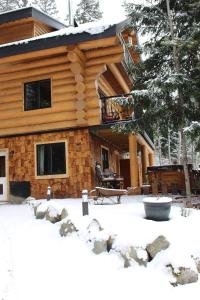 um chalé de madeira com uma varanda na neve em A Suite Retreat - Beyond Bed & Breakfast em Sun Peaks