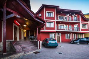 a red building with cars parked in front of it at Pensiunea Christiana in Arad