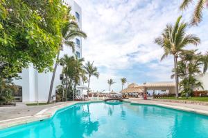 a swimming pool in front of a building with palm trees at Gaviana Resort in Mazatlán