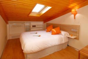 ein Schlafzimmer mit einem großen weißen Bett mit orangefarbenen Kissen in der Unterkunft Hostal riMboMbin in Burgos